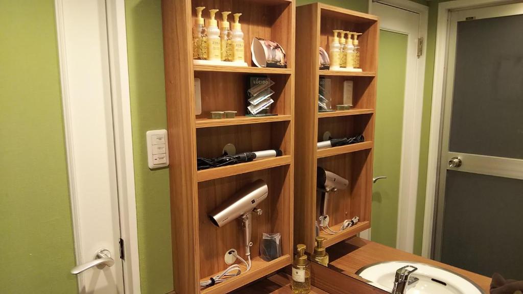 La salle de bains est pourvue d'une étagère en bois au-dessus d'un lavabo. dans l'établissement Xenia Amagasaki, à Amagasaki