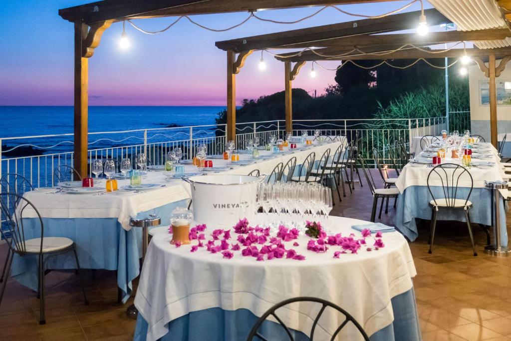 un groupe de tables avec des fleurs roses sur elles dans l'établissement Hotel Ferretti, à Diamante