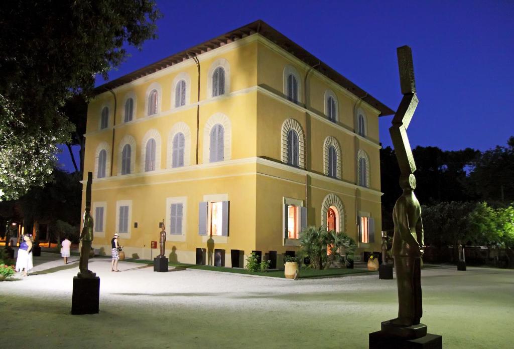 un grand bâtiment jaune avec une statue devant lui dans l'établissement Hotel Verdesolemare, à Marina di Pietrasanta