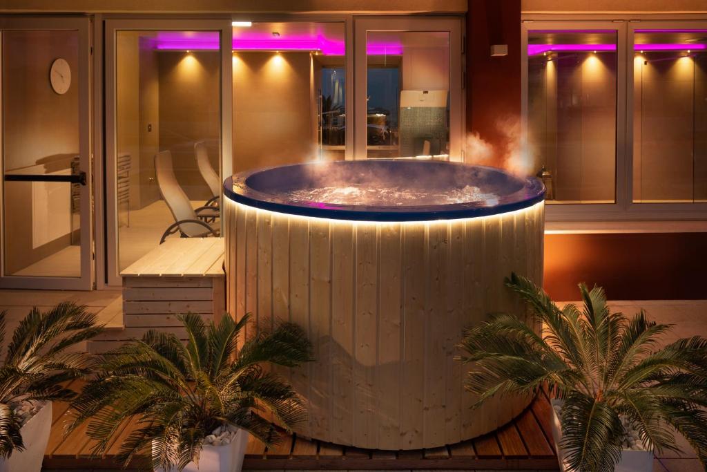 - une grande baignoire dans une chambre avec des palmiers dans l'établissement Hotel Ascot & Spa, à Rimini