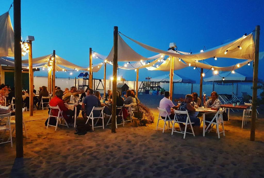 un groupe de personnes assises à des tables sur la plage la nuit dans l'établissement Alba Hotel, à Marina di Ravenna