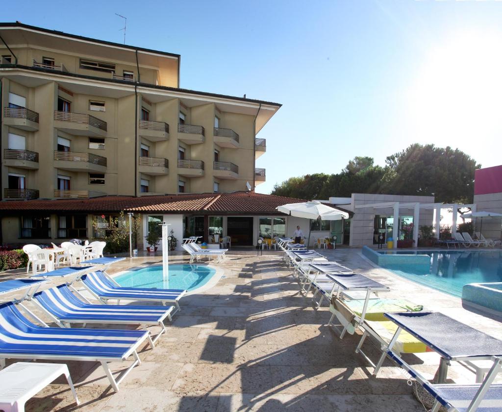 un hôtel avec des chaises longues et une piscine dans l'établissement Hotel Bristol, à Lignano Sabbiadoro