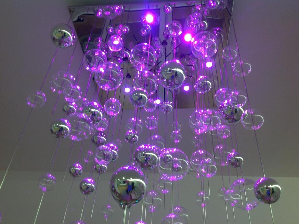 un lustre avec des lumières violettes suspendu au plafond dans l'établissement Hotel Lux, à Caorle
