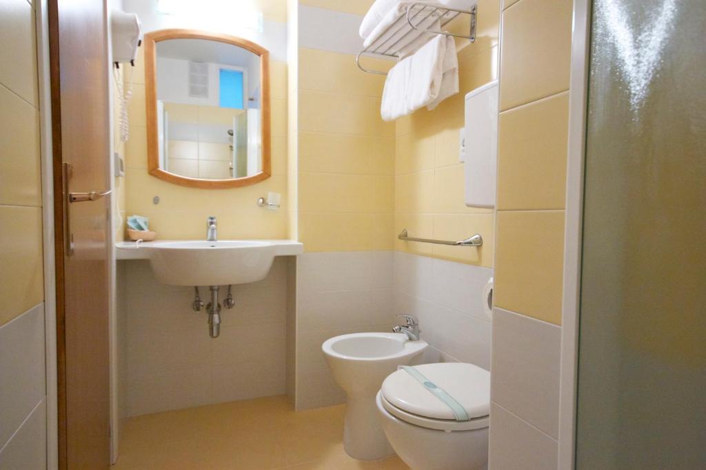 une salle de bain avec un lavabo, des toilettes et un miroir dans l'établissement Hotel Toledo, à Lido di Jesolo 73 autres photos