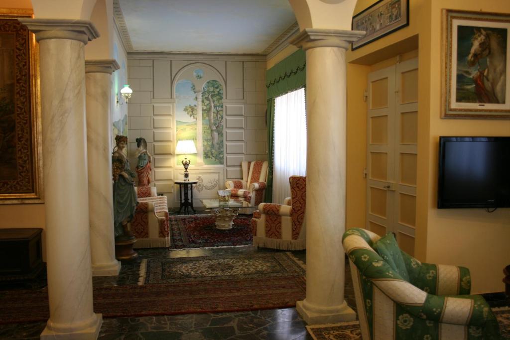 un salon avec des colonnes et une télévision dans la chambre dans l'établissement Villa Cappuccini, à Castiglion Fiorentino
