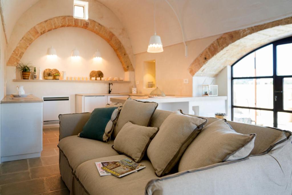 un salon avec un canapé et une cuisine dans l'établissement Dimora Sighé, exclusive rural villa with hydromassage pool, à Alessano