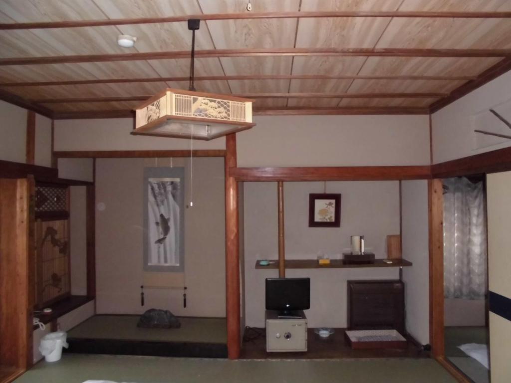 un salon avec un plafond en bois et une lumière dans l'établissement Minshuku Katsuya, à Shirahama