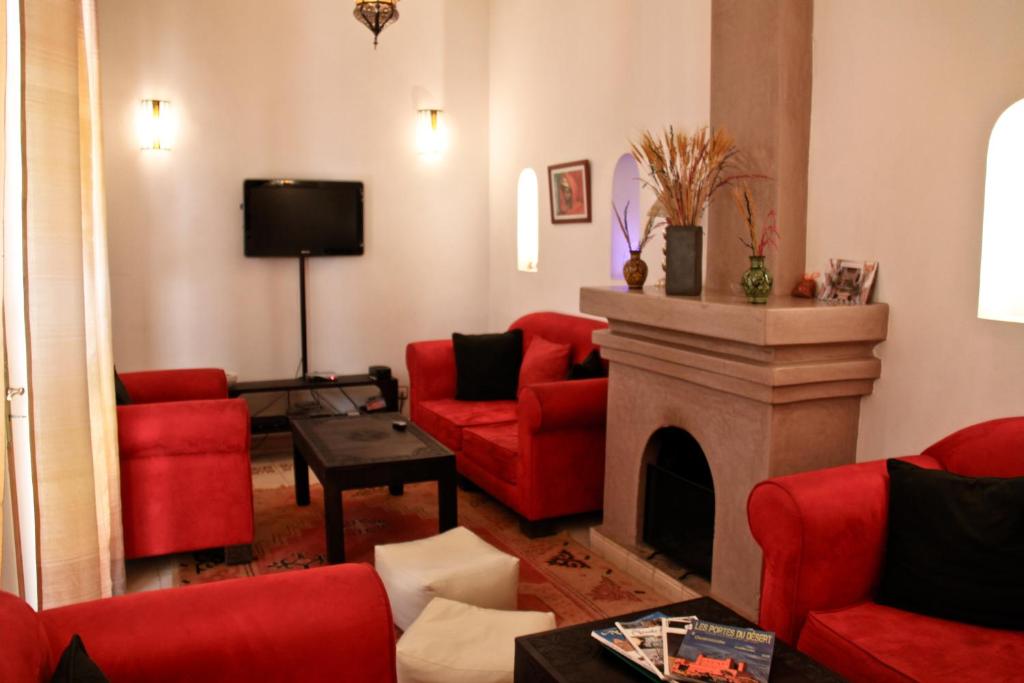 un salon avec des meubles rouges et une cheminée dans l'établissement Riad Mariana, à Marrakech
