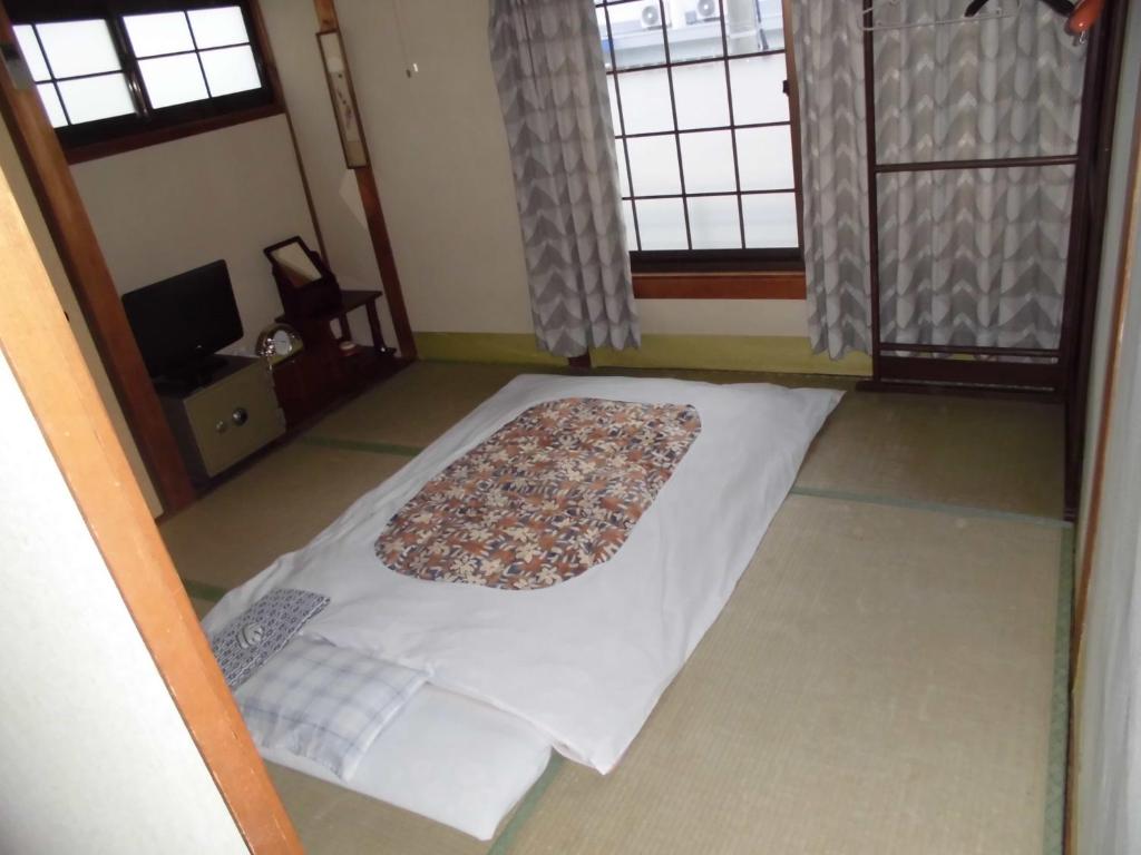 - un lit dans une chambre avec 2 fenêtres dans l'établissement Minshuku Katsuya, à Shirahama