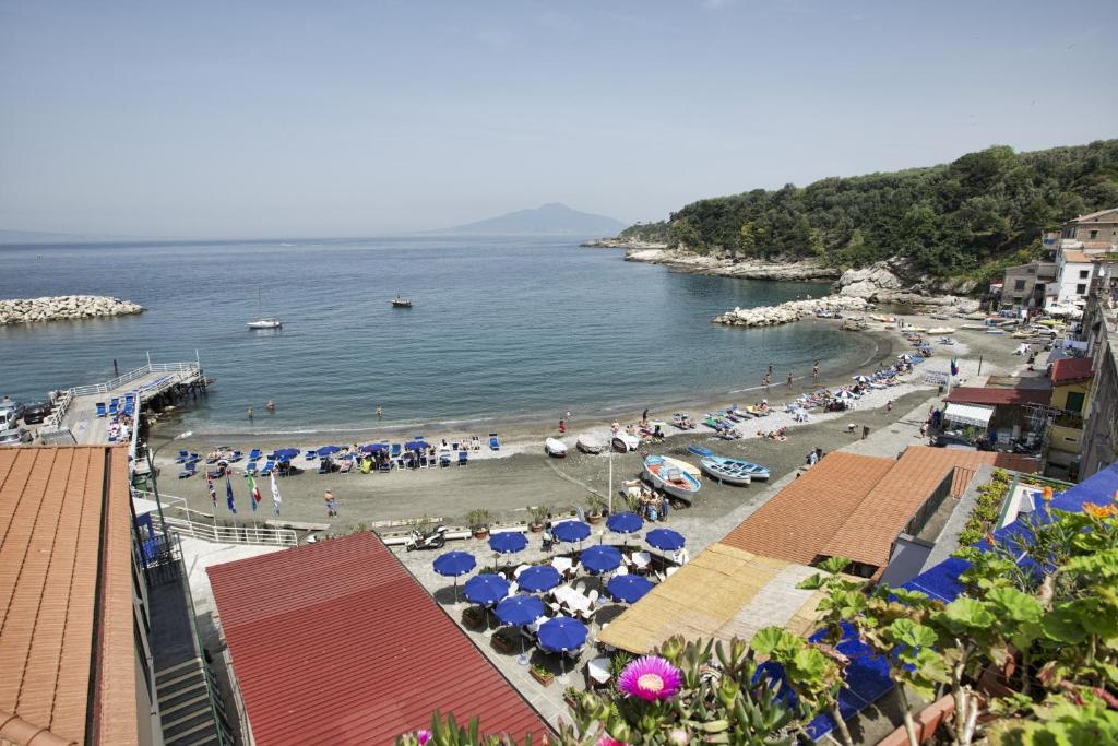 une plage avec des parasols et une foule de gens dans l'établissement Hotel Baia Di Puolo, à Massa Lubrense