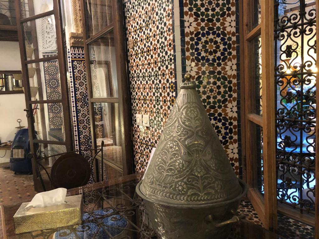 un grand vase en verre assis devant un mur dans l'établissement Riad Marhaba, à Rabat