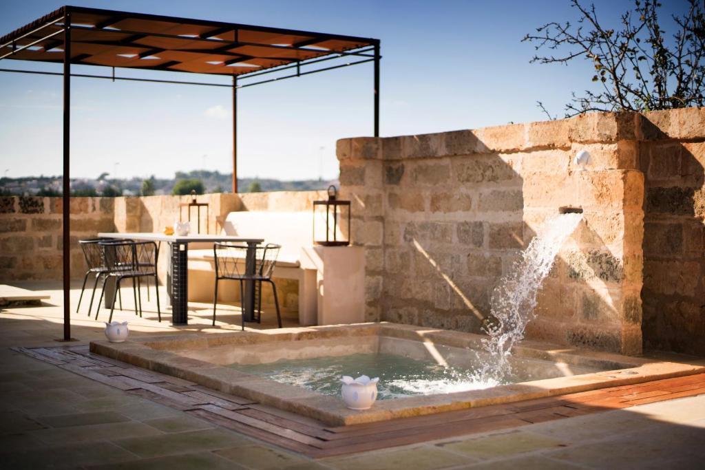 une fontaine sur une terrasse avec une table et des chaises dans l'établissement Dimora Sighé, exclusive rural villa with hydromassage pool, à Alessano