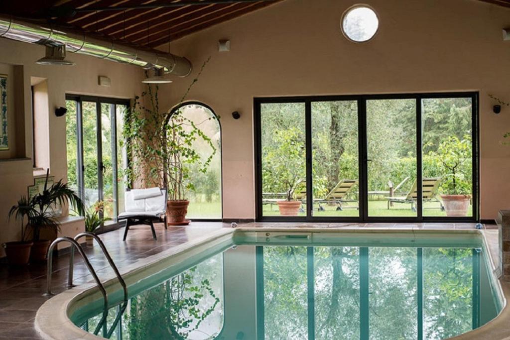 - une piscine dans une maison avec une chambre dotée de fenêtres dans l'établissement Montebelli Agriturismo & Country Hotel, à Caldana