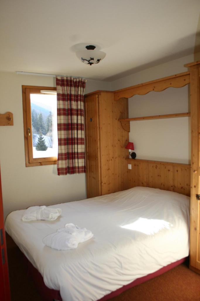 une chambre avec un grand lit blanc avec une fenêtre dans l'établissement Les Alpages De Val Cenis, à Lanslebourg-Mont-Cenis