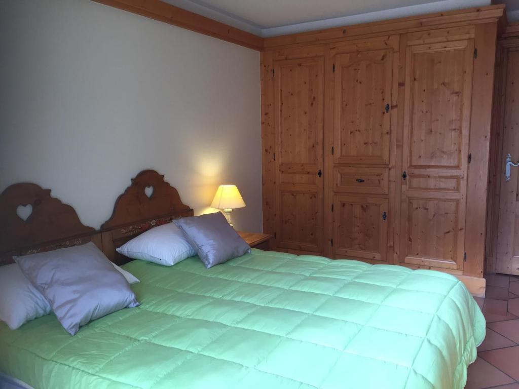 - une chambre avec un grand lit vert et des placards en bois dans l'établissement Front Ski Slope Chamonix Apartment, à Chamonix-Mont-Blanc
