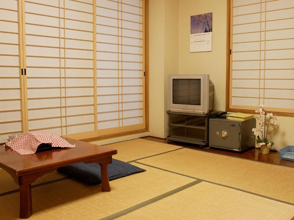 un salon avec une table et une télévision dans l'établissement Kakiya Ryokan, à Kamakura