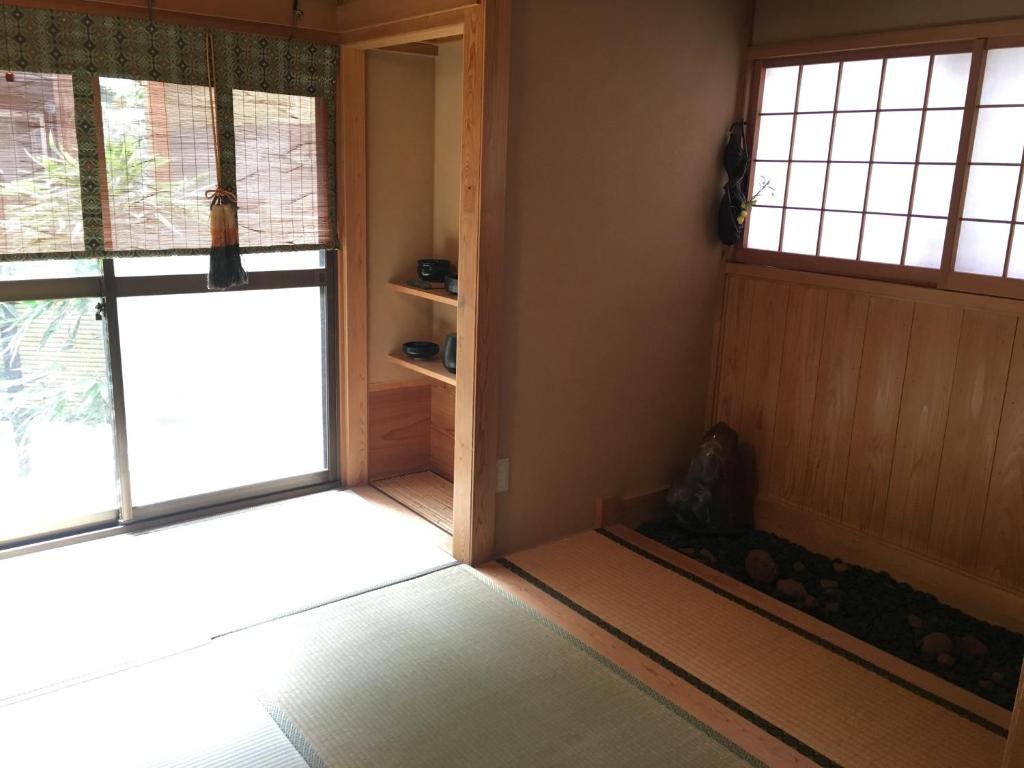 une pièce vide avec deux fenêtres et une porte dans l'établissement Masugataya Ryokan, à Tako