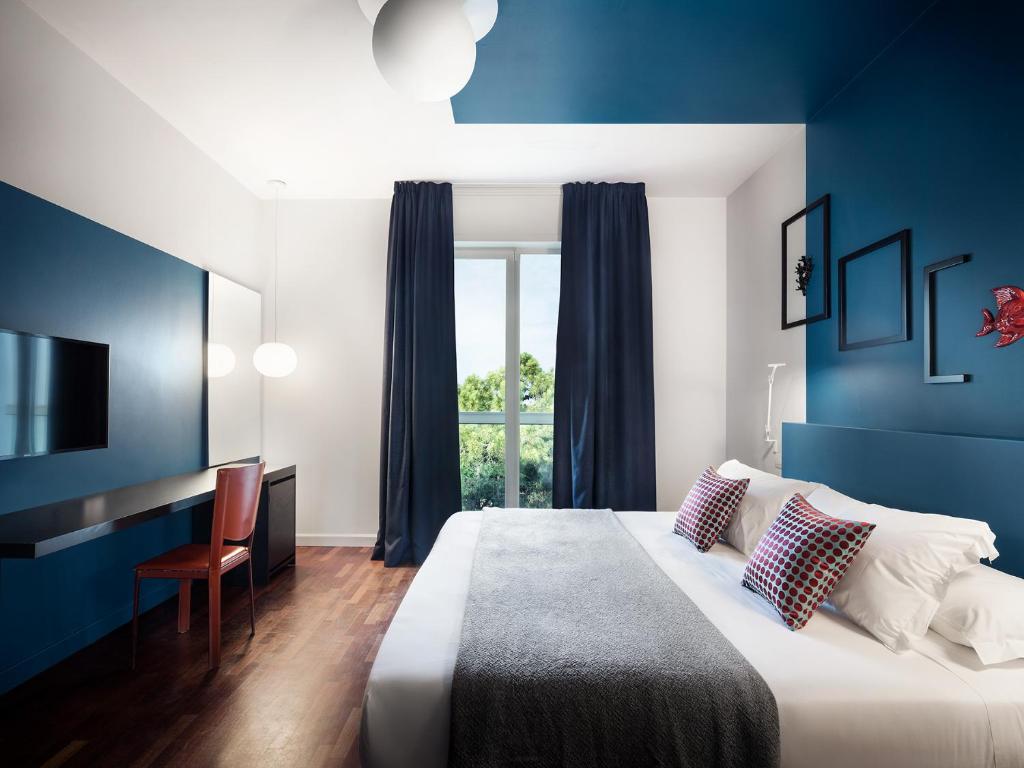 - une chambre avec des murs bleus et un lit avec un bureau dans l'établissement Villa Regina - MarePineta Resort, à Milano Marittima