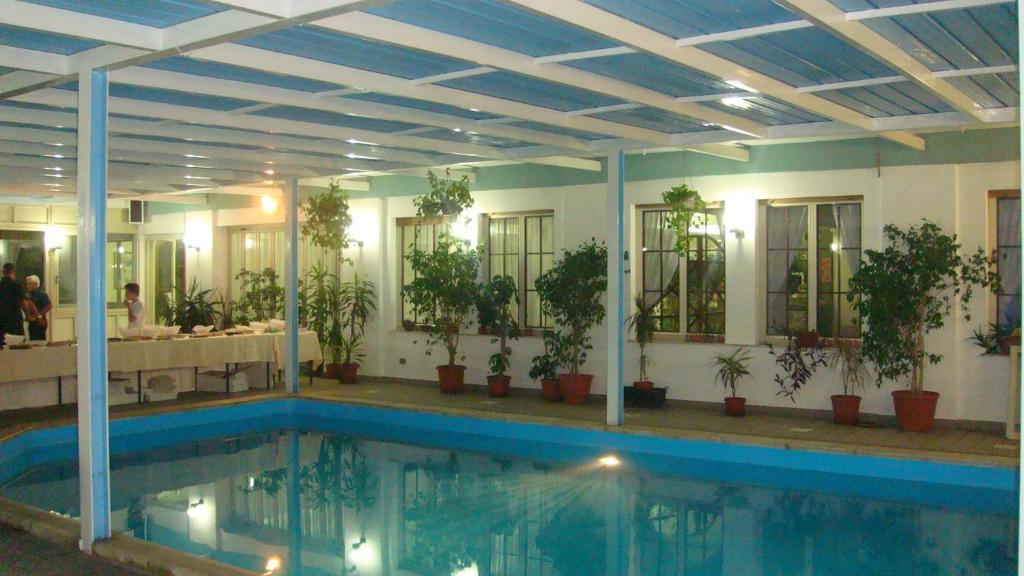 une piscine dans un bâtiment avec des plantes et des miroirs dans l'établissement Hotel Kennedy, à SantʼAlessio Siculo