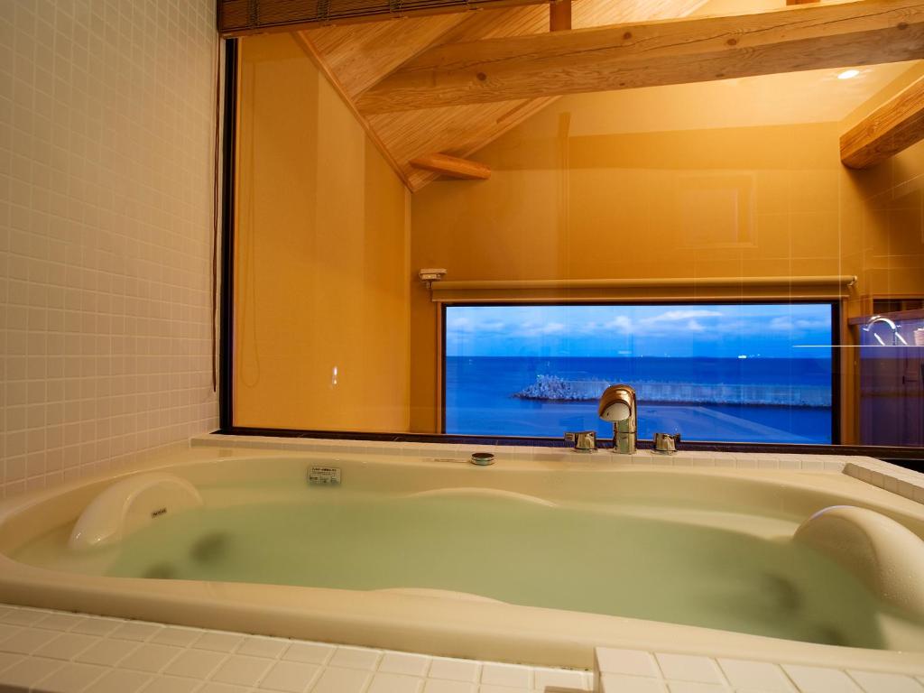 une baignoire dans une salle de bain avec une fenêtre dans l'établissement Amahara, à Sumoto