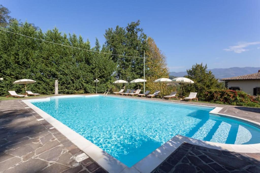 une piscine avec chaises et parasols dans l'établissement Villa Eugenia Tuscany with private Pool, Sauna & Gym, à Vicchio