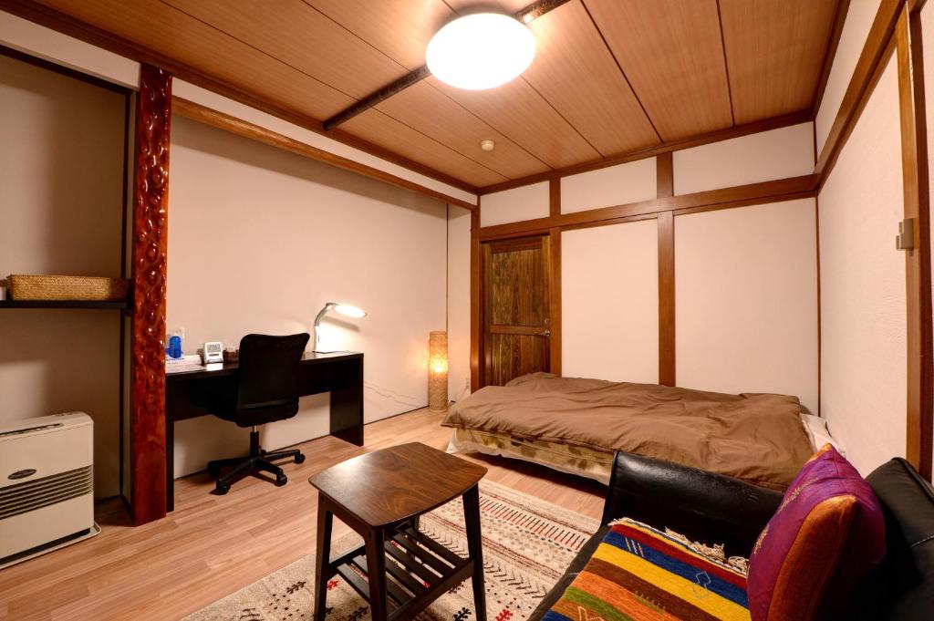 une chambre avec un lit, un bureau et une chaise dans l'établissement Azuma Ryokan, à Kitakata