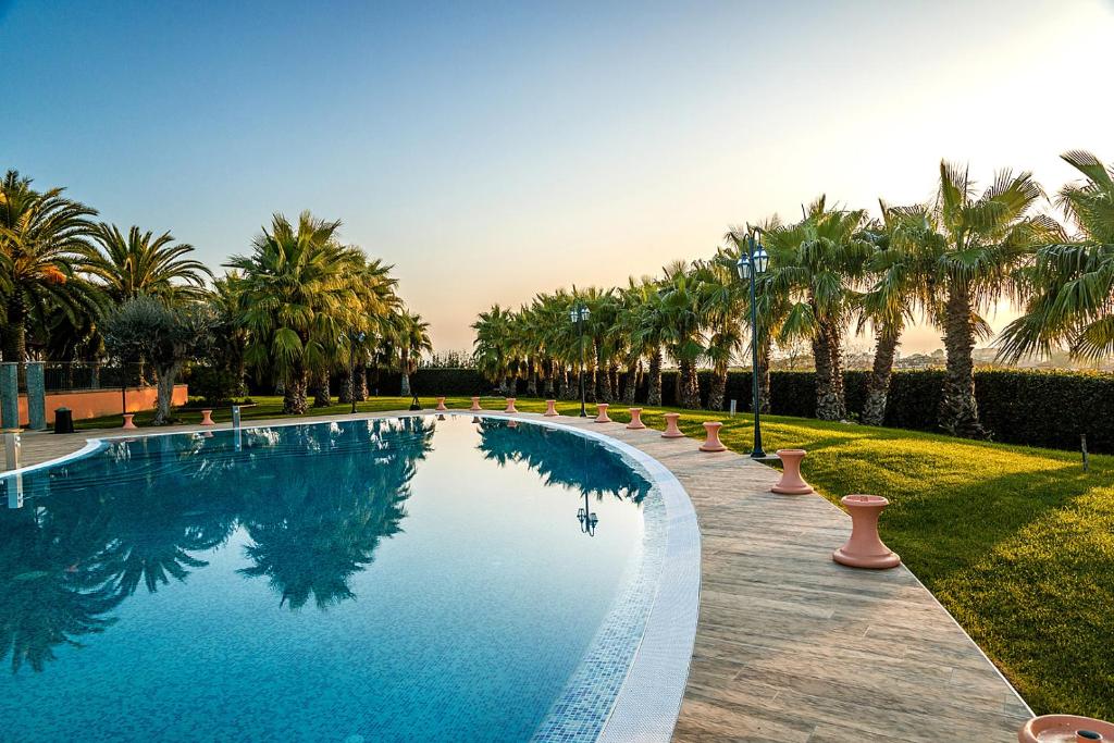 une piscine entourée de palmiers dans un parc dans l'établissement Villa Luigi Hotel & Restaurant Nuova gestione, à Martinsicuro
