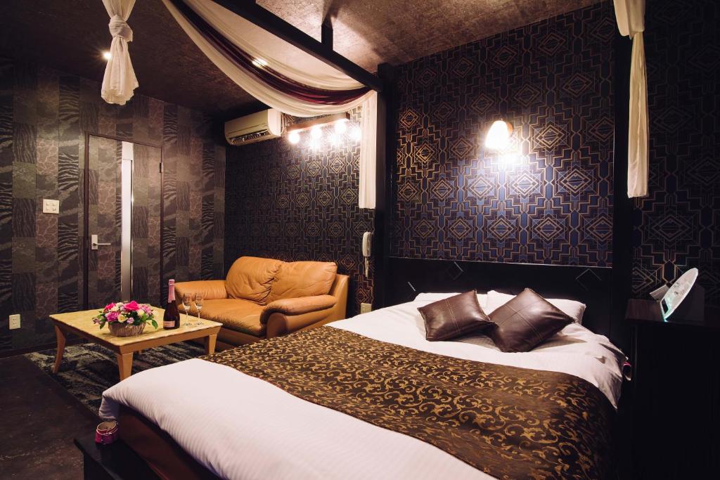 une chambre d'hôtel avec un lit et une chaise dans l'établissement Tinkerbell (Adult Only), à Takamatsu