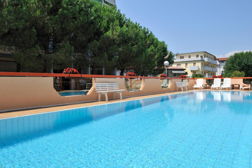 une grande piscine avec des chaises sur un bâtiment dans l'établissement Hotel President, à Bibione