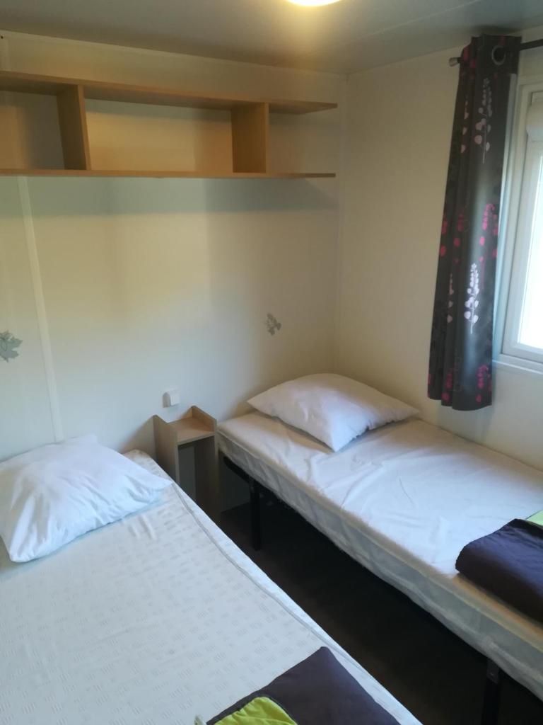 deux lits dans une chambre avec deux fenêtres dans l'établissement MH Camping 4* face Royan, à Soulac-sur-Mer
