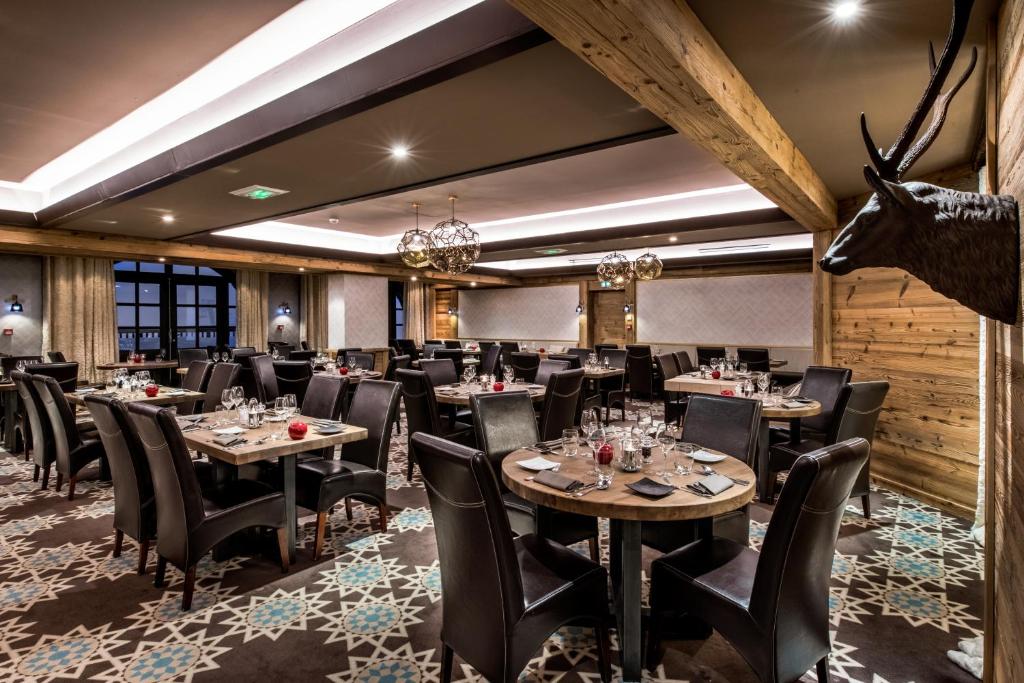 un restaurant avec des tables et des chaises et une tête de cerf sur le mur dans l'établissement Hôtel Les Suites du Montana by Les Etincelles, à Tignes
