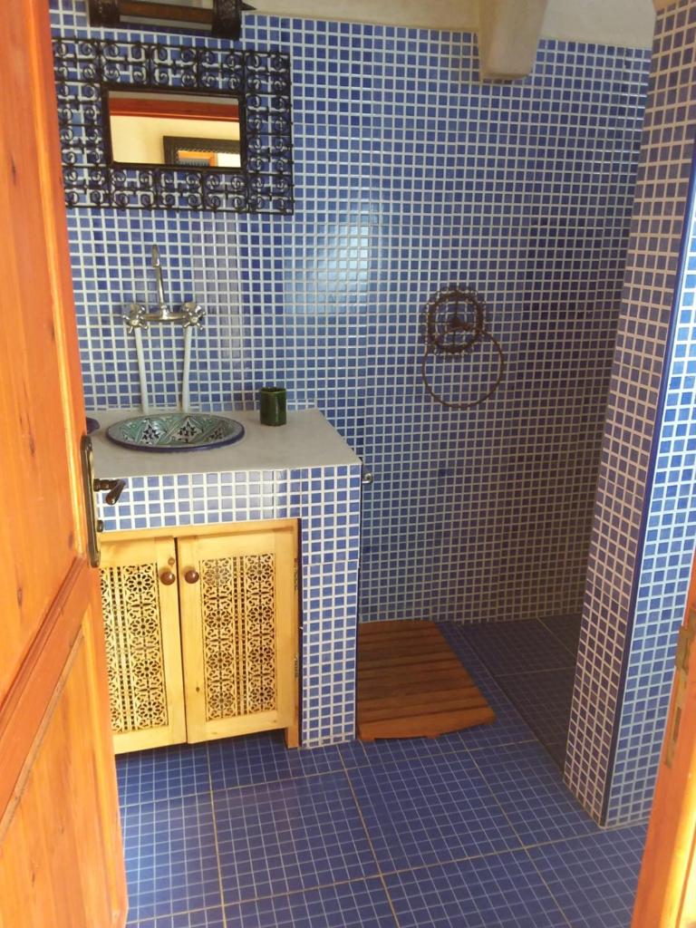 La salle de bains est pourvue d'un lavabo et d'un mur carrelé bleu. dans l'établissement Maison du Soleil, à Tiznit