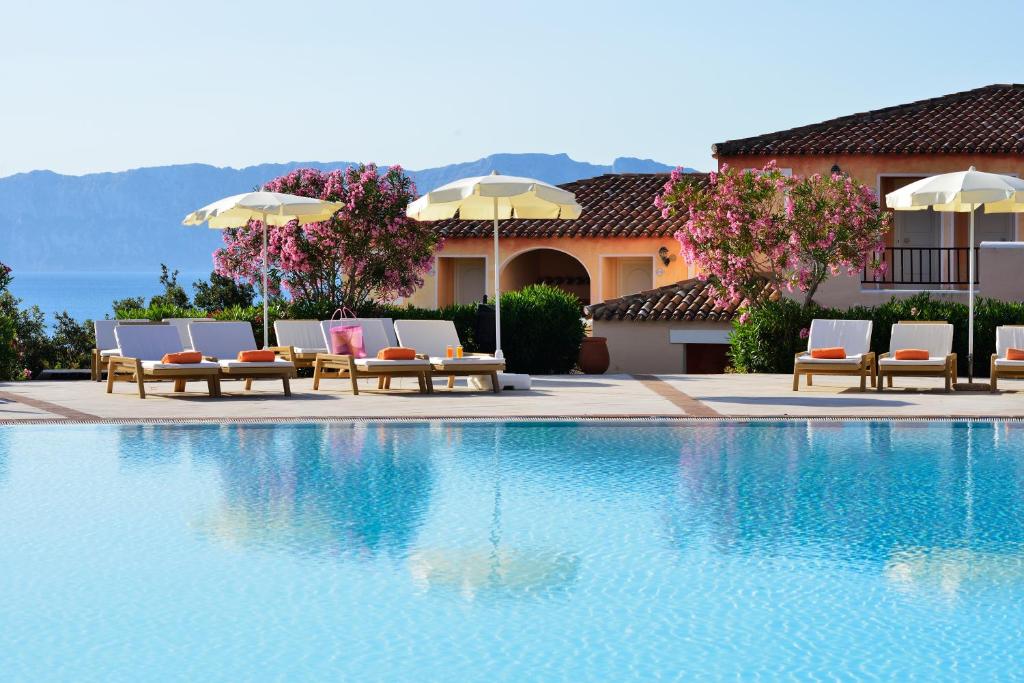 - une piscine avec des chaises et des parasols à côté d'un bâtiment dans l'établissement VOI Colonna Village, à Golfo Aranci