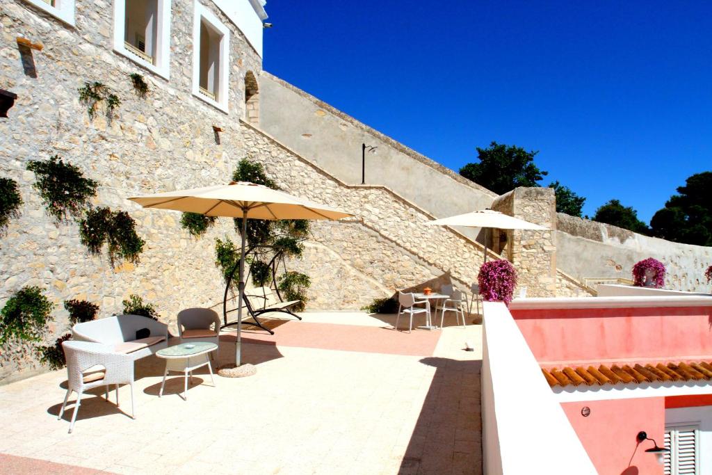 un patio avec des tables et des parasols à côté d'un bâtiment dans l'établissement Hotel Boutique Il Castellino Relais, à Vieste