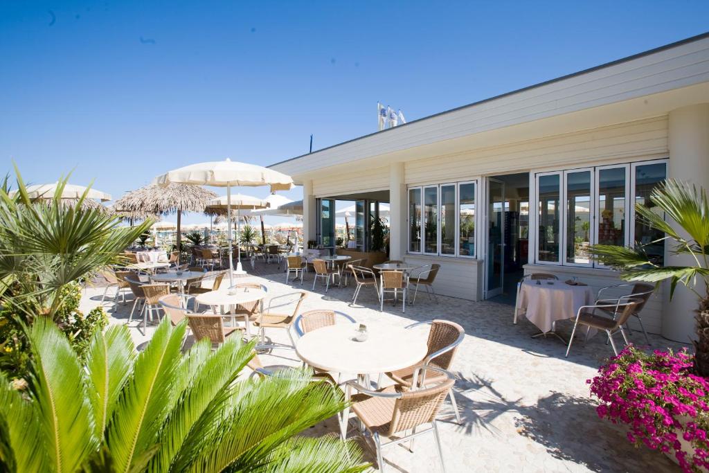 un patio extérieur avec tables, chaises et parasols dans l'établissement Hotel Waldorf- Premier Resort, à Milano Marittima