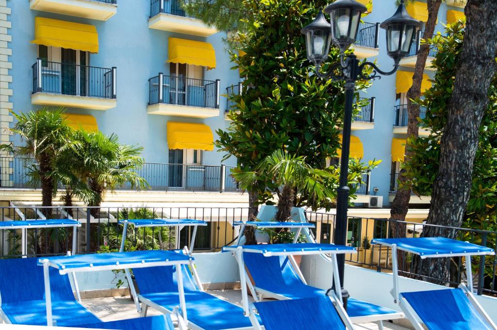 un groupe de tables et de chaises bleues devant un bâtiment dans l'établissement Hotel Fabrizio, à Rimini