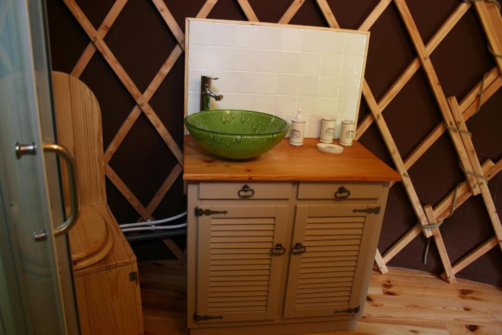 - une salle de bains avec un bol vert au-dessus d'un comptoir dans l'établissement Yourtes en Terrasse, à Bonneval 37 autres photos