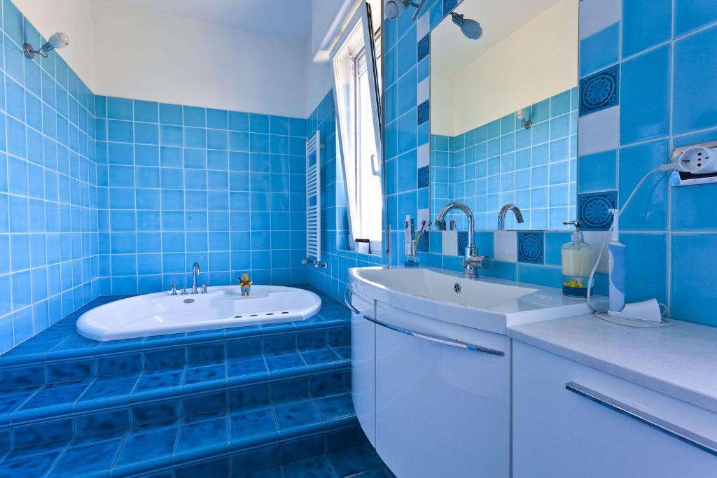une salle de bain carrelée bleue avec deux lavabos et une baignoire dans l'établissement VILLA DIADEMA, à Vezzi Portio