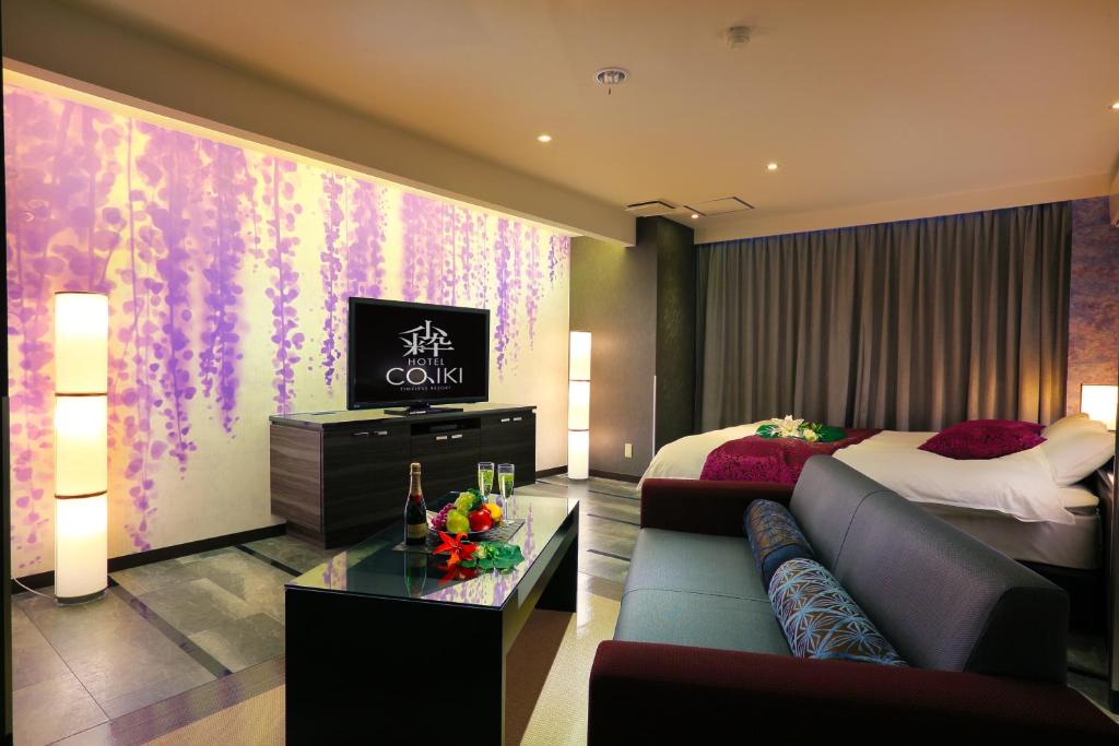 une chambre d'hôtel avec un lit, un canapé et une télévision dans l'établissement HOTEL 小粋 -coiki-, à Hiroshima