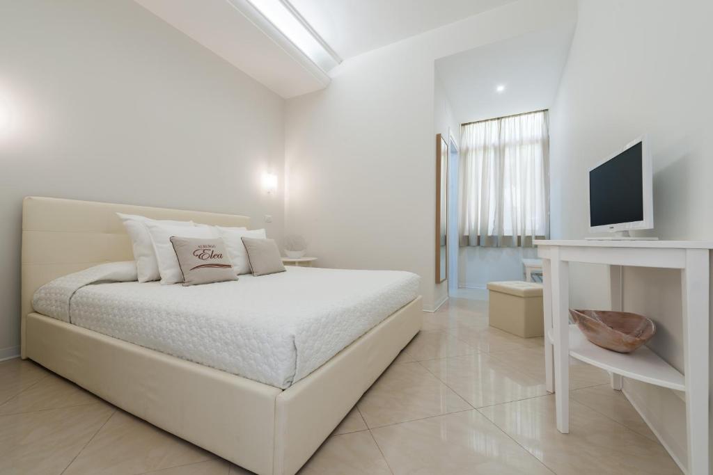 une chambre blanche avec un lit et une télévision dans l'établissement Albergo Elea, à Ascea