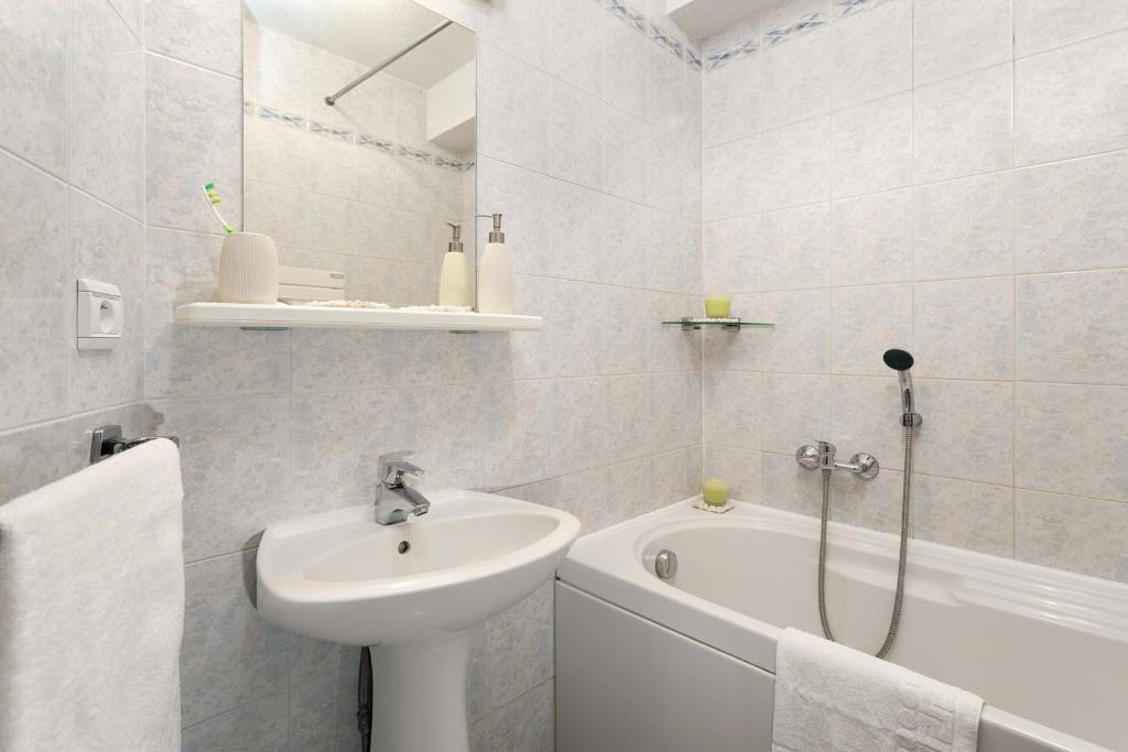 une salle de bain blanche avec un lavabo et une baignoire dans l'établissement Madame Vacances Lodges des Alpages, à La Plagne