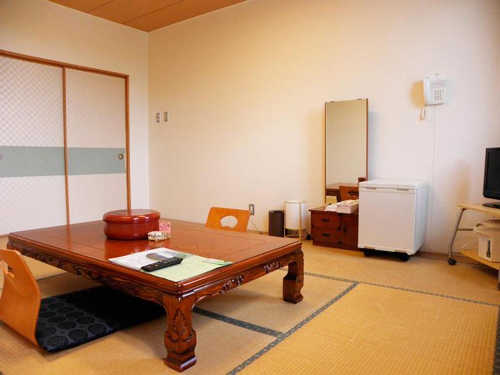un salon avec une table en bois et une télévision dans l'établissement Kurplaza Pirika, à Hanaishi 14 autres photos