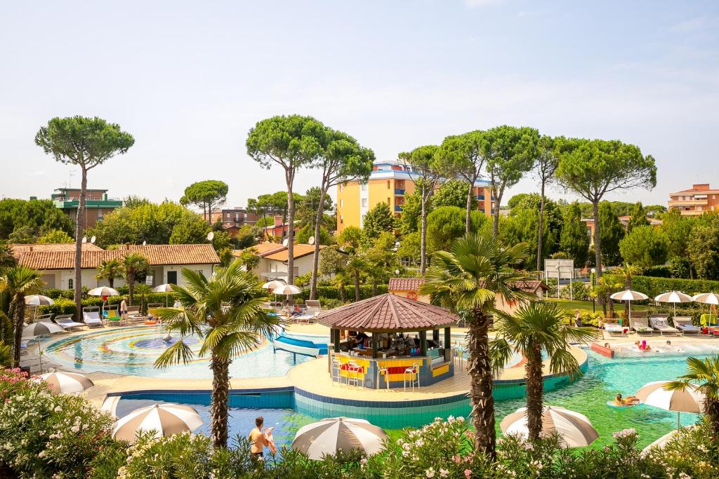 une piscine dans un complexe hôtelier avec des palmiers dans l'établissement Mediterranee Family Hotel & Spa, à Bibione