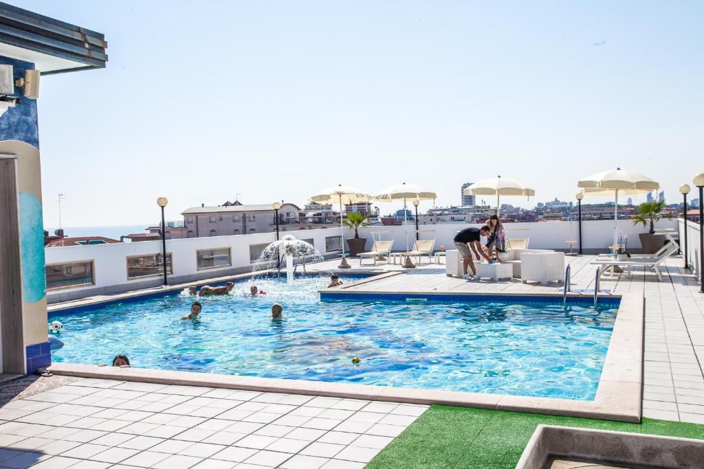 une piscine sur le toit d'un immeuble avec des gens dedans dans l'établissement Hotel Christian, à Lido di Jesolo