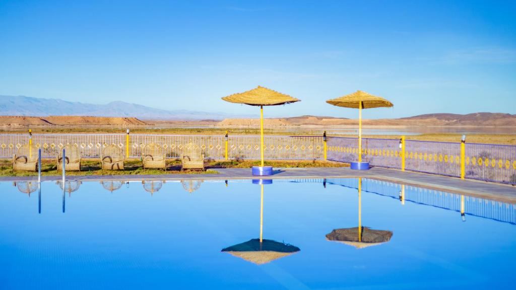 une piscine d'eau avec parasols et chaises dans l'établissement Ecolodge l'île de Ouarzazate, à Ouarzazate