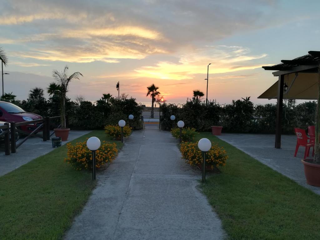 une allée avec des lumières blanches dans un parc au coucher du soleil dans l'établissement Residence Santa Barbara, à San Ferdinando