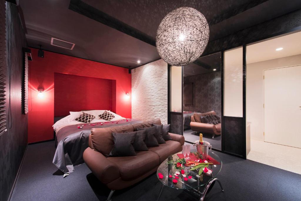 une chambre avec des murs rouges et un lit et un canapé dans l'établissement Hotel LUNE CLAIRE (Adult Only), à Chikuma