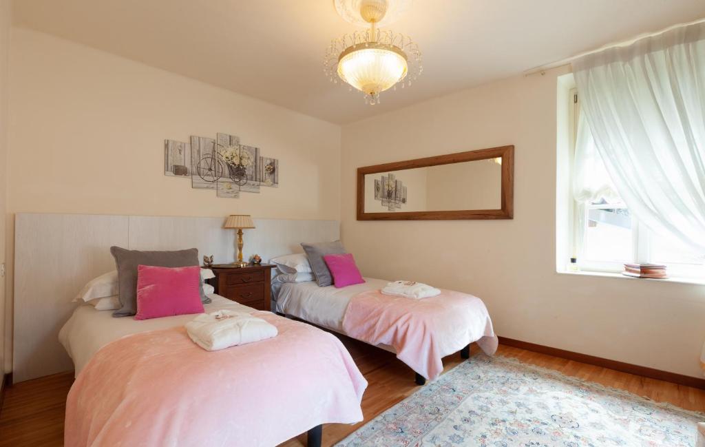 une chambre avec deux lits avec des draps roses et un miroir dans l'établissement Villa La Dolce Vita, à Oliveto Lario 29 autres photos