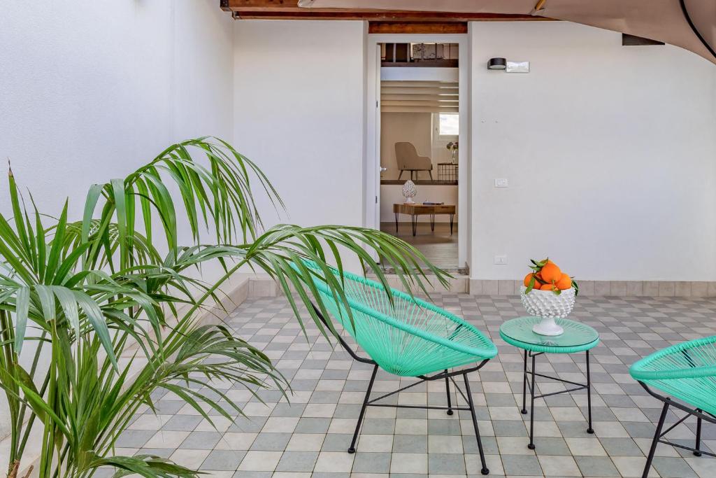 un patio avec deux chaises vertes et une table et des plantes dans l'établissement Le Maestranze Deluxe Rooms, à Sciacca