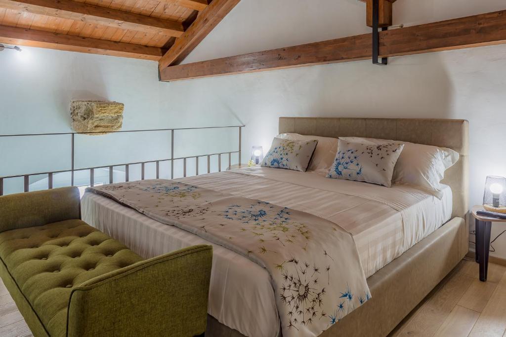 une chambre avec un grand lit et une chaise dans l'établissement Le Maestranze Deluxe Rooms, à Sciacca